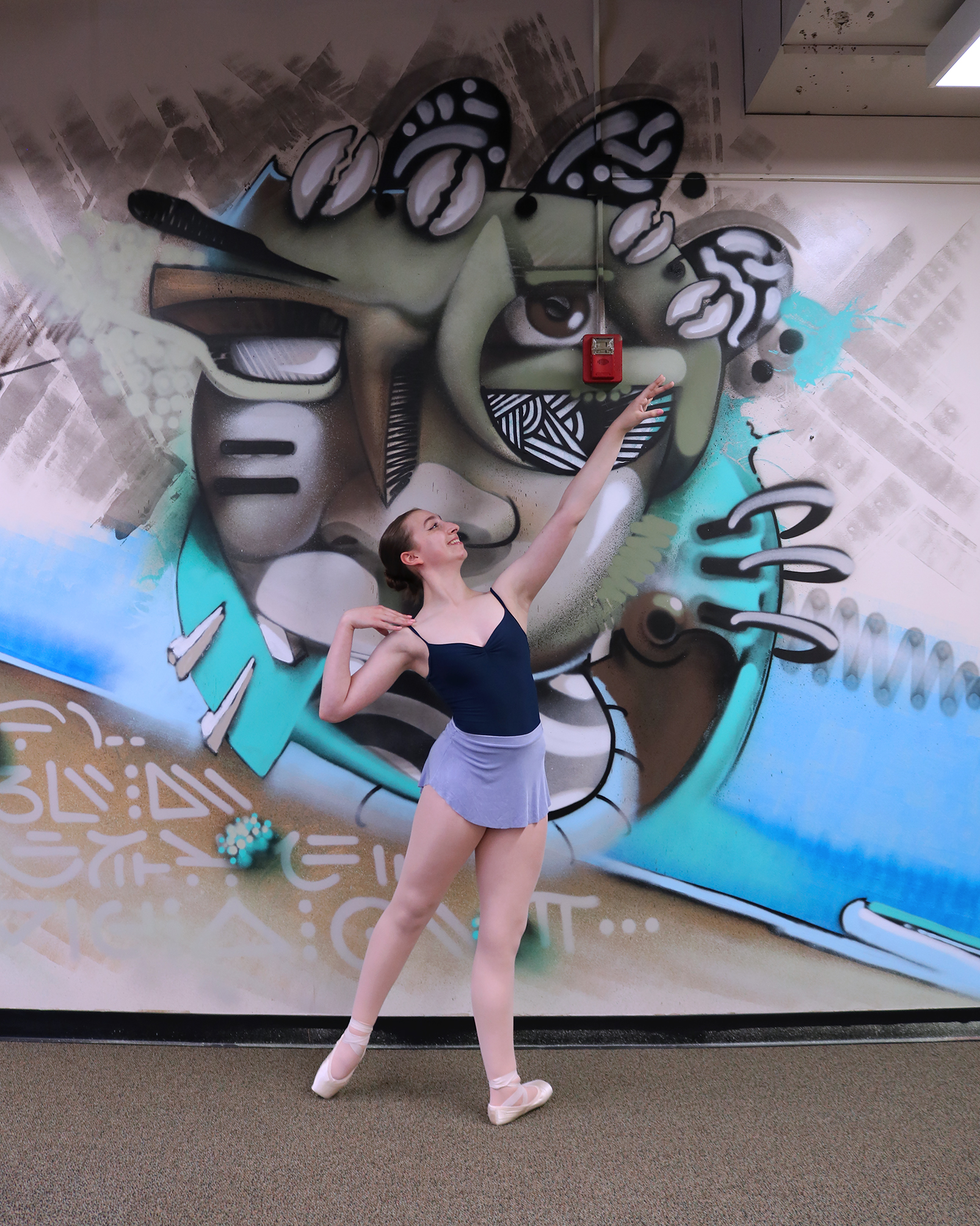 Ballerina en pointe in front of a wall mural.