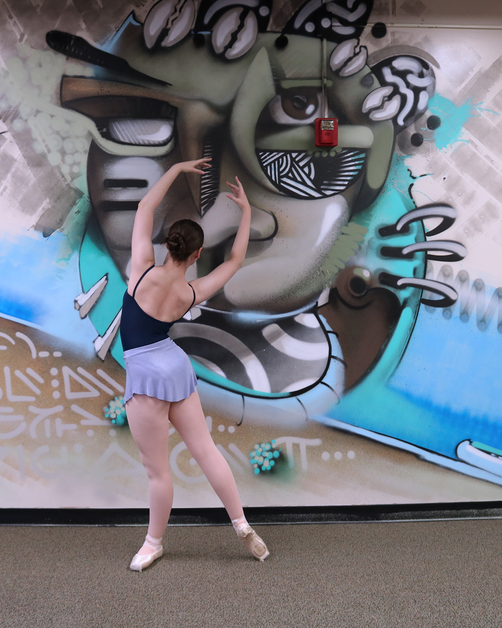 Ballerina in front of a wall mural.